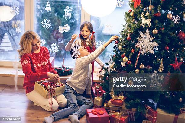 family decorating christmas tree - family christmas tree stock pictures, royalty-free photos & images