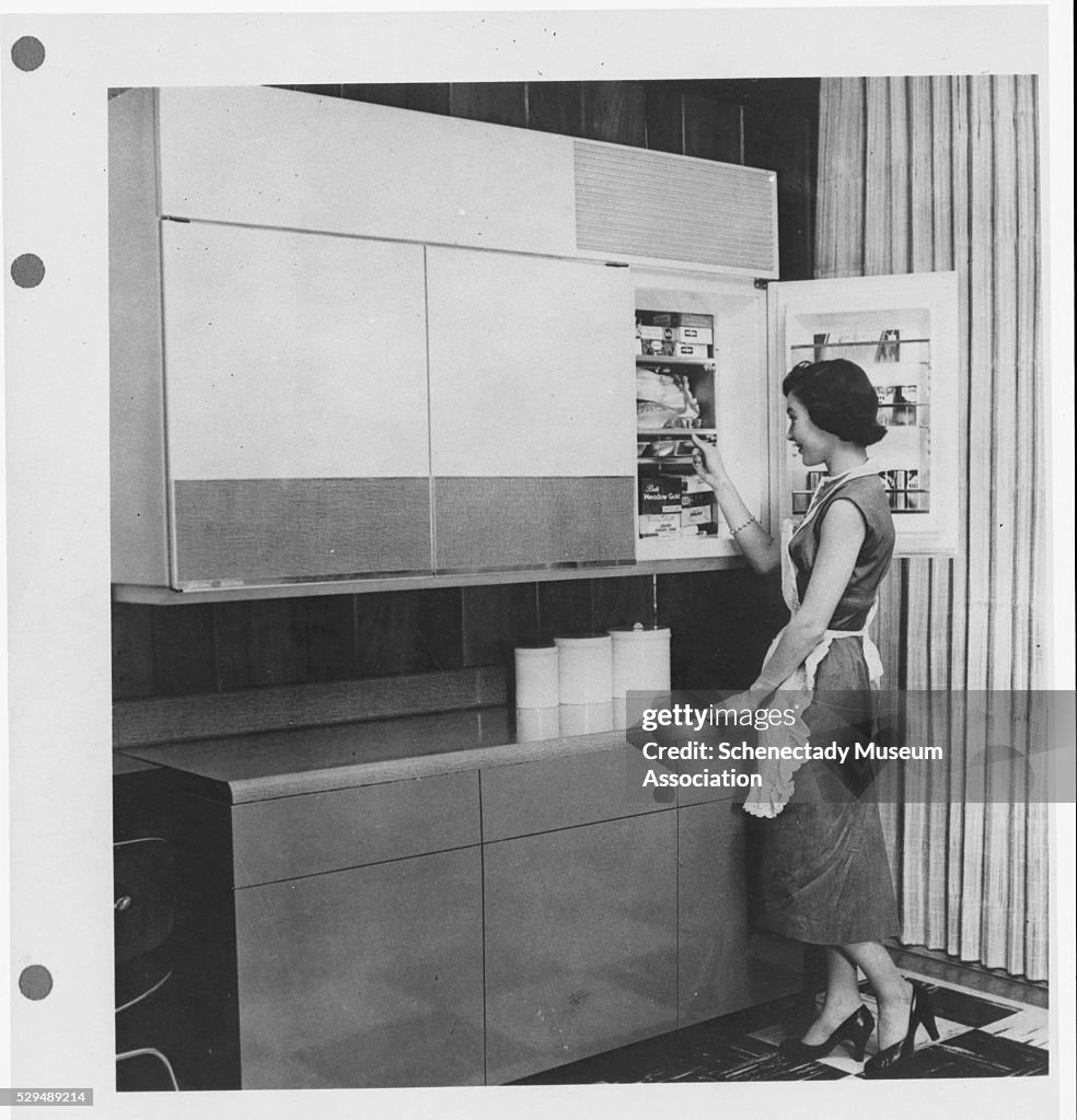 Woman Next to a Wall Mounted Refrigerator