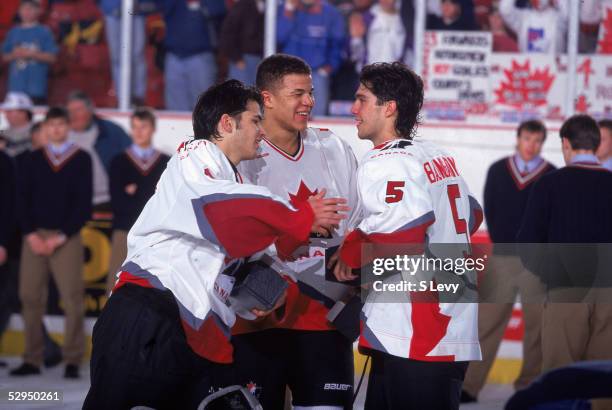 On the ice, Canadian hockey players Jose Theodore, Jerome Ignila, and Nolan Baumgartner celebrate Team Canada's victory at the 1996 World Junior Ice...