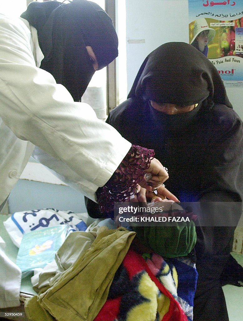 A yemeni woman holds her child while bei