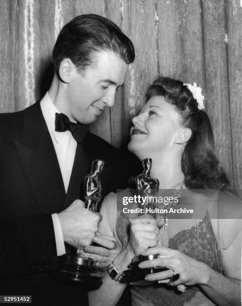 American actors James Stewart and Ginger Rogers , arms locked and Oscars in hand, gaze into each other's eyes at the 1940 Academy Awards banquet, Los...
