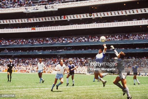 Diego Maradona of Argentina handles the ball past Peter Shilton of England to score the opening goal of the World Cup Quarter Final at the Azteca...