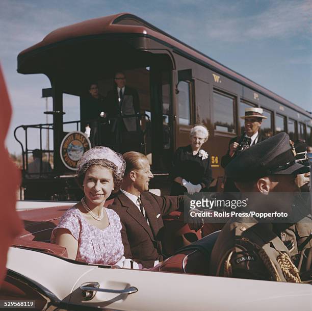 Queen Elizabeth II and Prince Philip Mountbatten, Duke of Edinburgh pictured sitting in the back seat of an open top car in Whitehorse, Yukon during...