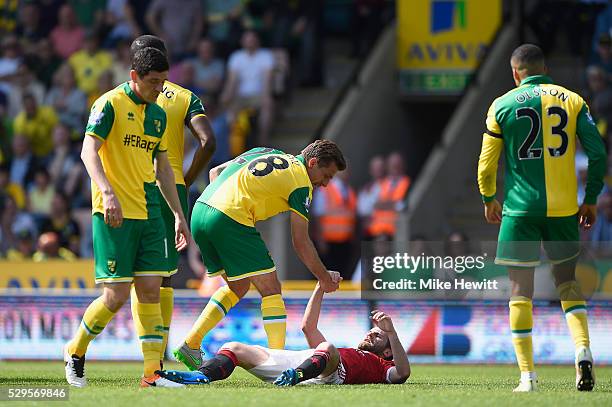 Juan Mata of Manchester United is helped up by Gary O'Neil of Norwich City during the Barclays Premier League match between Norwich City and...