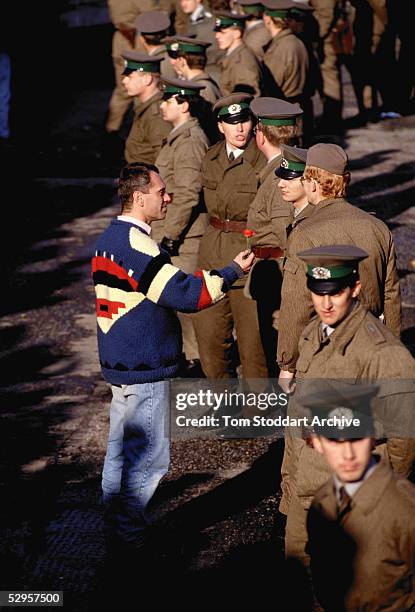 Man offers a flower as a sign of peace to East German border guards on the morning that the first section of the Berlin Wall was pulled down.