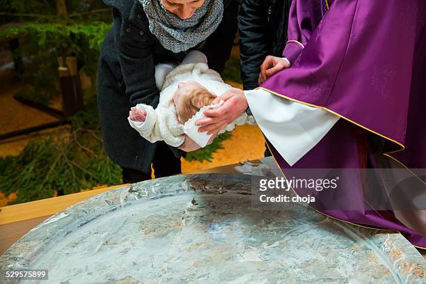 priest is baptizing little baby girl in a church - baptism girl stock pictures, royalty-free photos & images