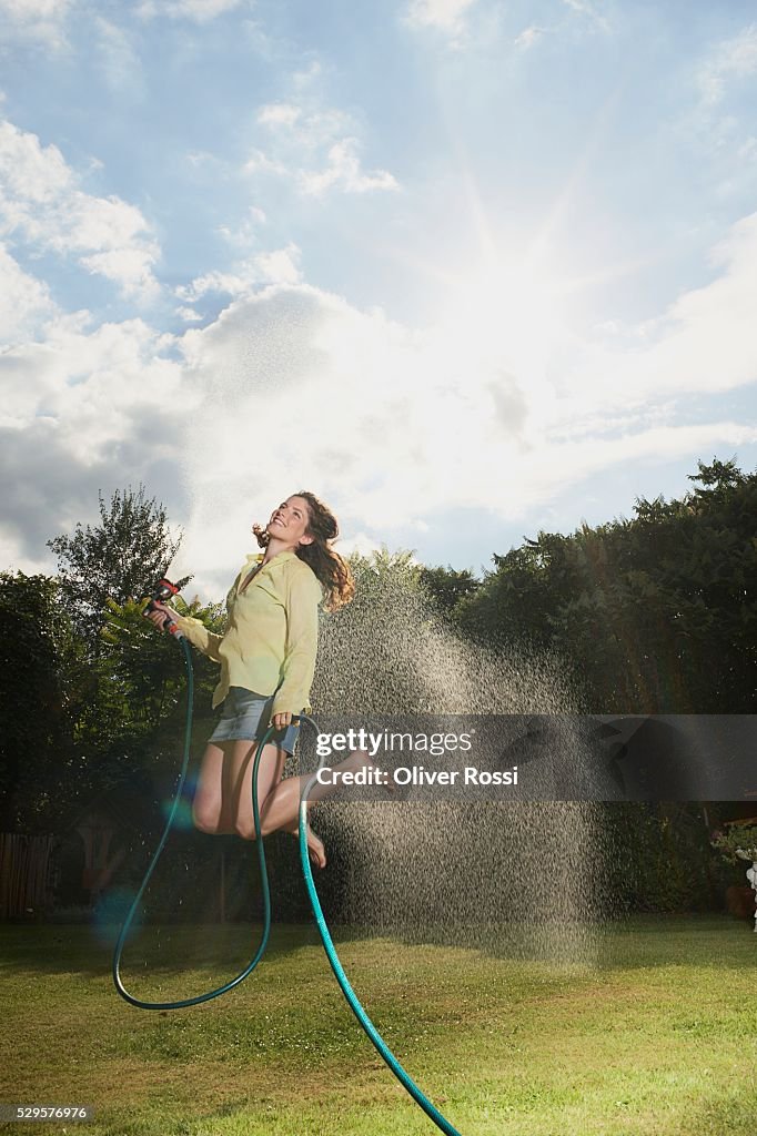 Woman Jumping with Garden Hose