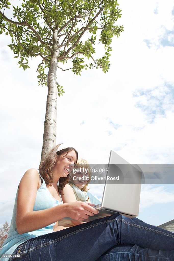 Two Women with Laptop Under a Tree