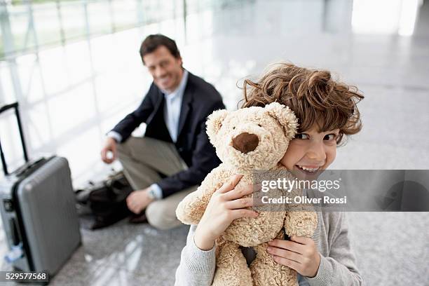 boy (5-6) holding teddy bear, father in background - child teddy bear stock-fotos und bilder