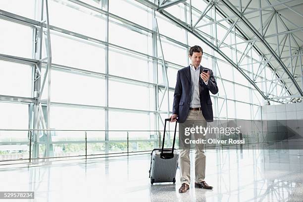 man with luggage in airport lobby - man airport stockfoto's en -beelden