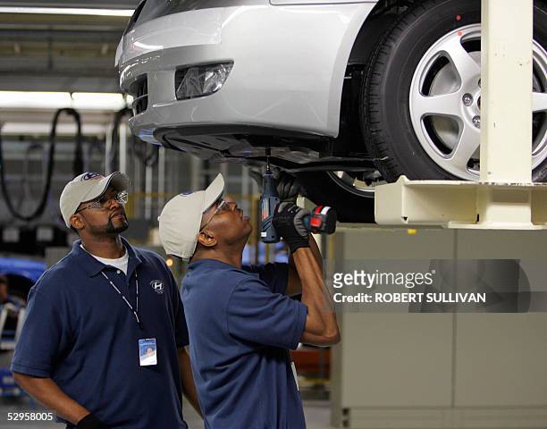 Hyundai employees work on the front end of a car as it rolls down the assembly line 20 May 2005 during the grand opening of their plant in...