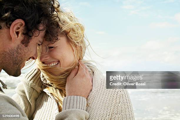 happy couple embracing on beach - cardigan stock pictures, royalty-free photos & images