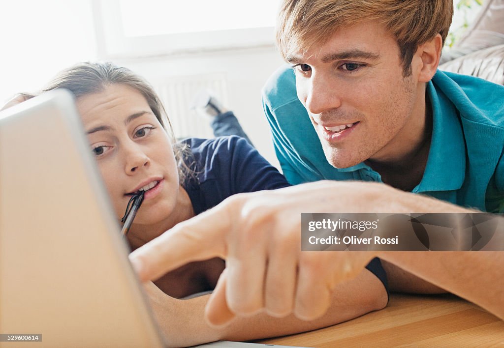 Teen (16-17) couple lying on floor using laptop