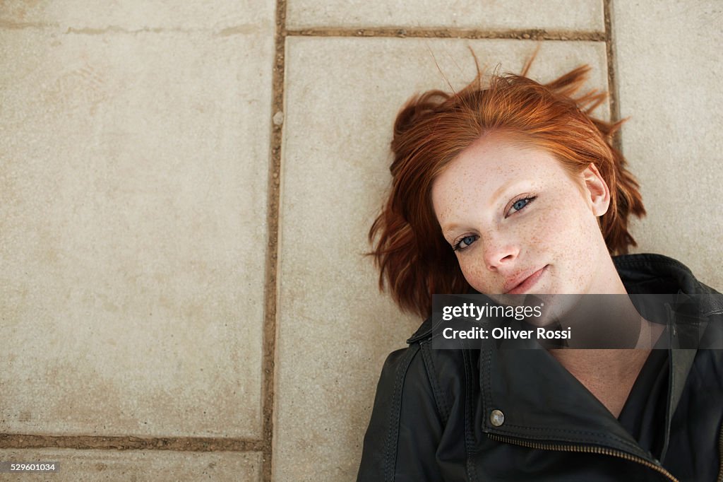 Portrait of teen (16-17) girl lying on pavement
