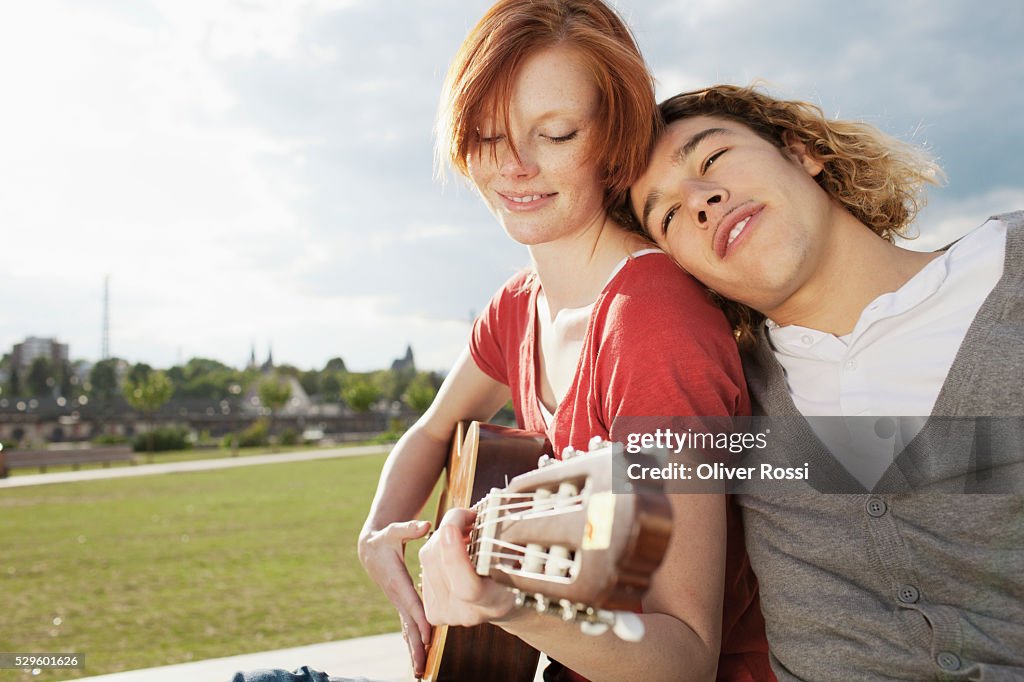 Young couple with guitar relaxing in park