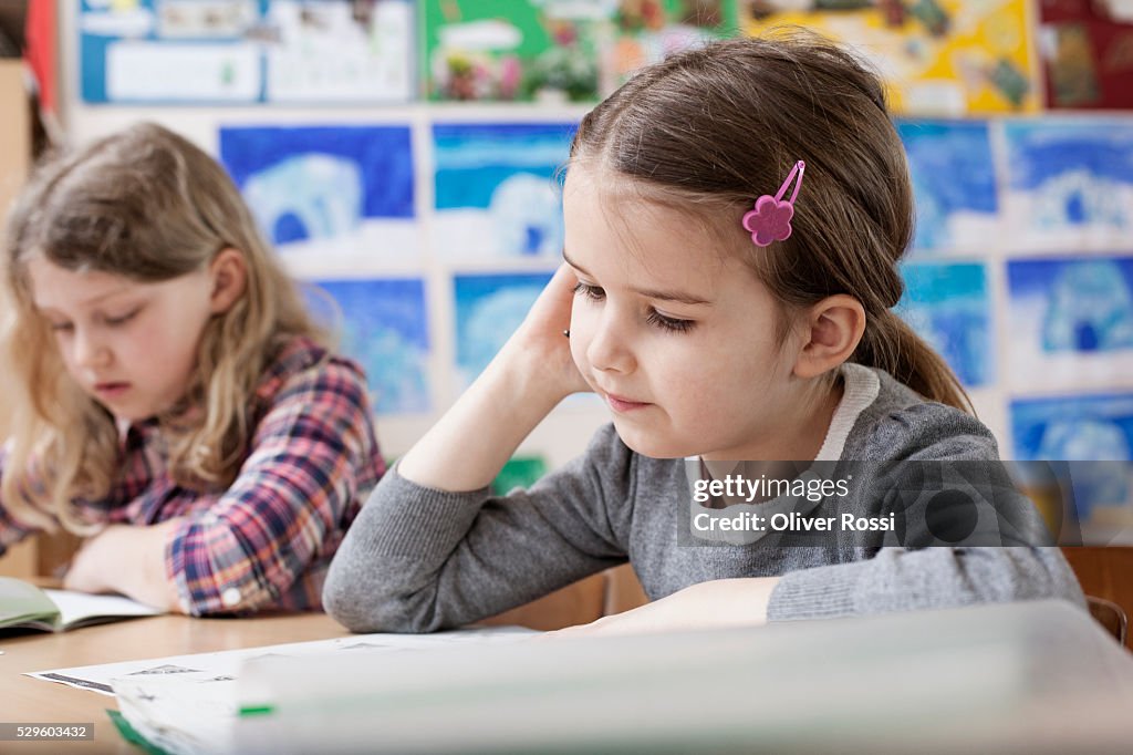 Two schoolgirls (6-7) reading in classroom