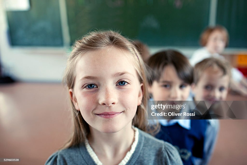 Group of schoolchildren (6-7) posing in front of blackboard