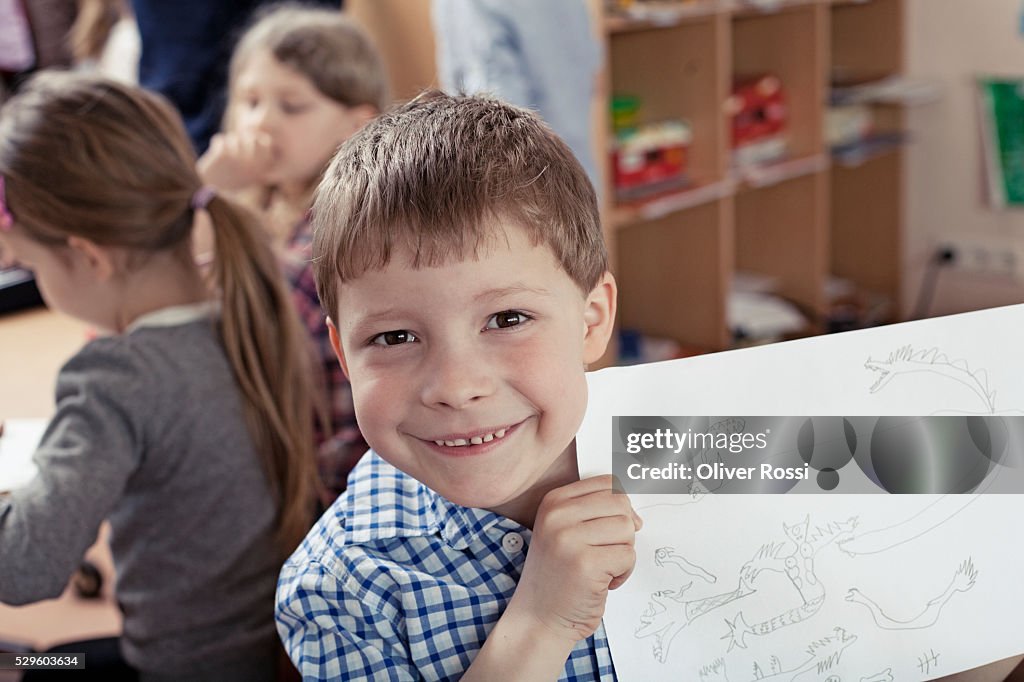 Young school boy (8-9) showing his drawing