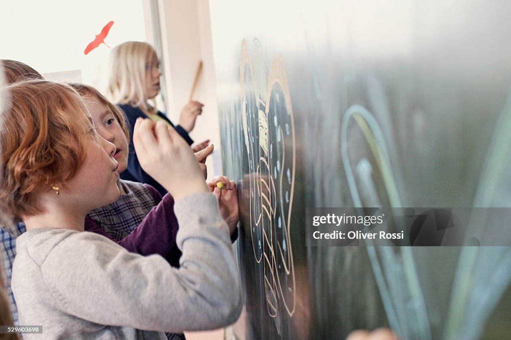 Girls and boys (6-7) painting in art class