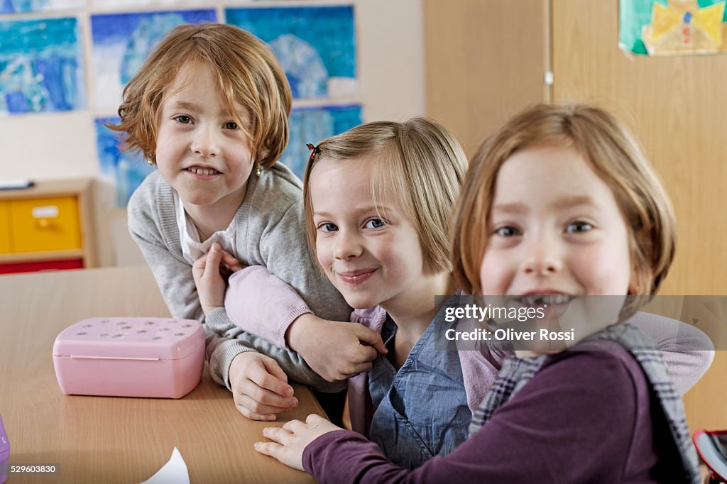 School boy (6-7) and two schoolgirls (6-7) sitting together in classroom