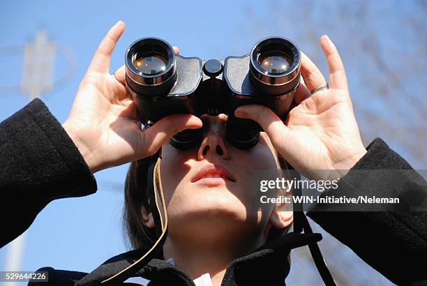 close-up of a young woman looking through binoculars, - looking through binoculars stock pictures, royalty-free photos & images