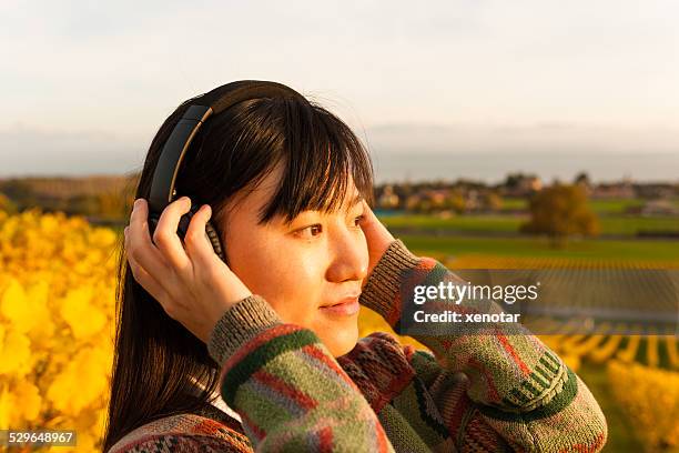 young woman standing in vineyard enjoy music - xenotar stockfoto's en -beelden