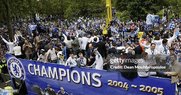 Chelsea players display the FA Barclays Premier League trophy and League Cup on team bus as they are surrounded by fans as they make their way down...