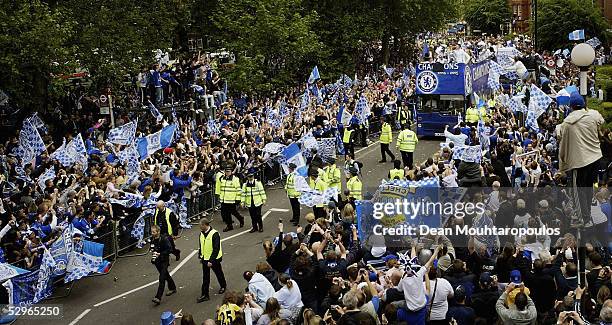 Chelsea players display the FA Barclays Premier League trophy and League Cup on team bus as they are surrounded by fans as they make their way down...