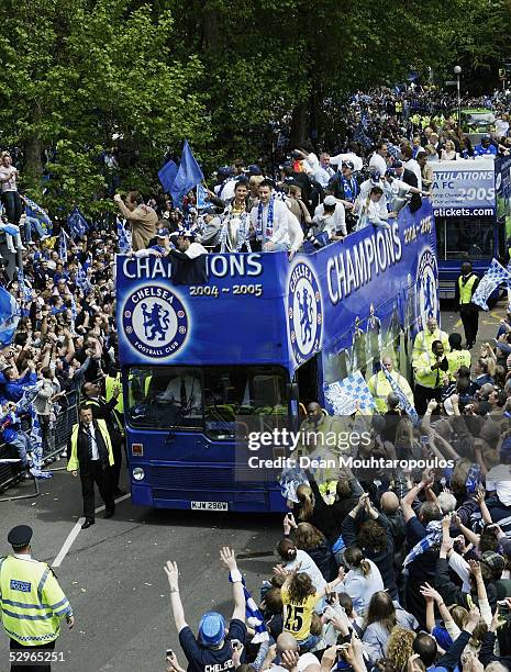 Chelsea players display the FA Barclays Premier League trophy and League Cup on team bus as they are surrounded by fans as they make their way down...