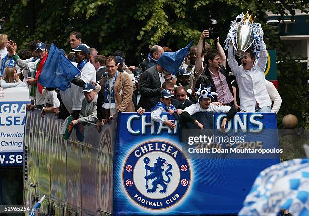 Chelsea players display the FA Barclays Premier League trophy and League Cup on team bus as they are surrounded by fans as they make their way down...