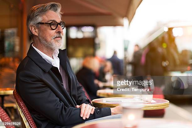 middle aged man sitting in a french terrace. - millionnaire stock pictures, royalty-free photos & images