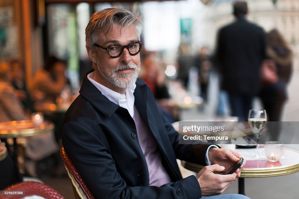 Middle aged man sitting in a french terrace.