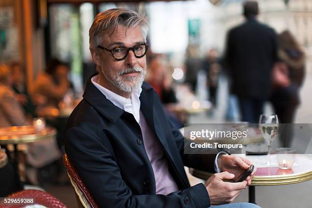 middle aged man sitting in a french terrace. - french cafe bildbanksfoton och bilder