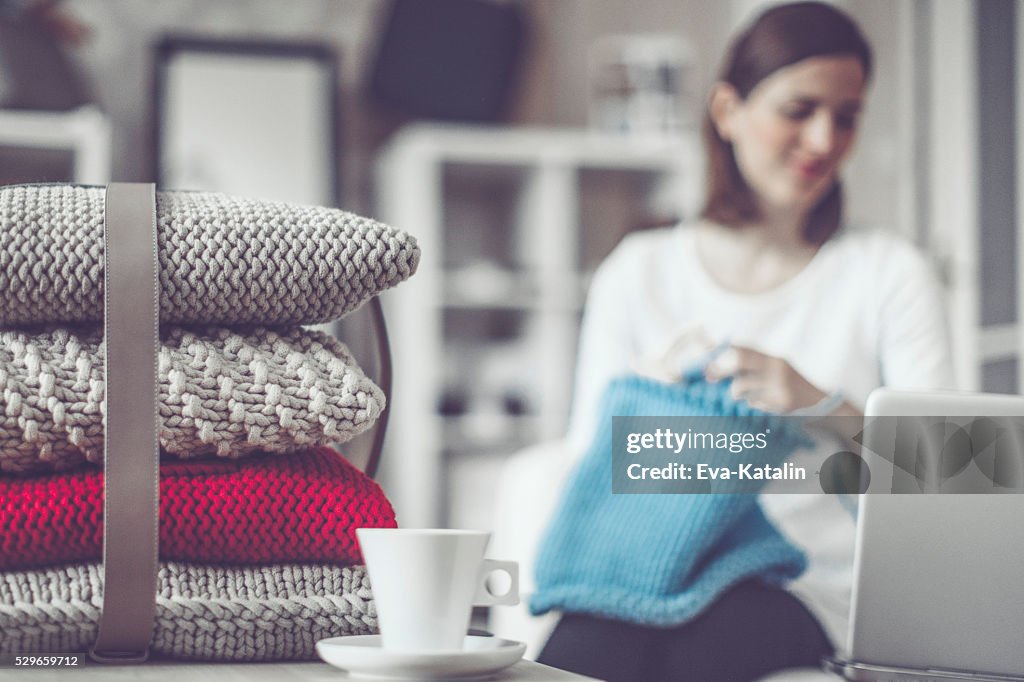 Fashion designer is knitting in her showroom