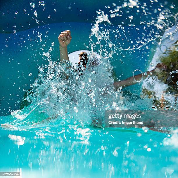 child sliding and splashing in water park - water slide stock pictures, royalty-free photos & images