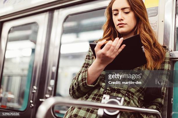 woman reading e-book in the subway - ereader stockfoto's en -beelden