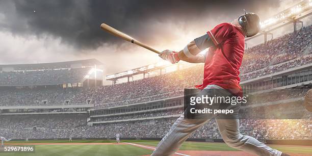 baseball player hitting ball during baseball game in outdoor stadium - baseball game stadium stockfoto's en -beelden