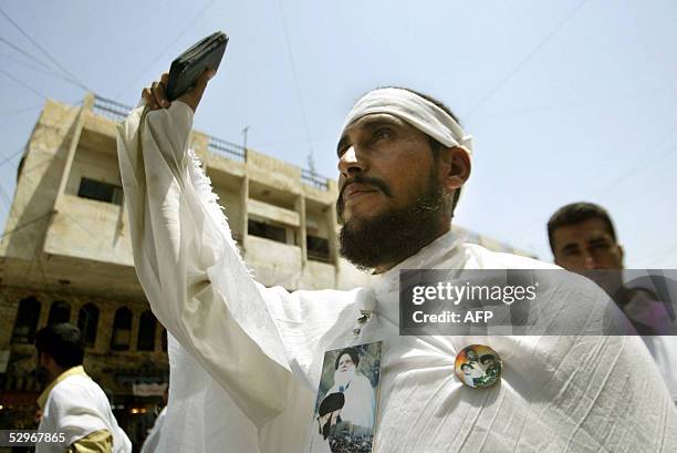 Shiite Muslim man wears a white death shroud as he holds up the Koran during a protest 23 May 2005, in Baghdad, days after an article was published...