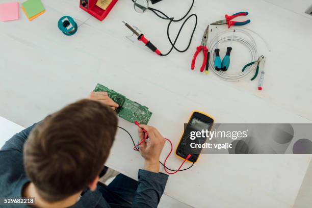 man soldering a circuit board in his tech office. - soldered stock pictures, royalty-free photos & images