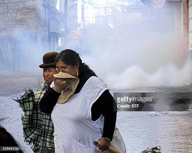 Women cover their mouth after anti riot police threw tear gas during a protest in demand of the nationalization of the gas and oil resources, in La...