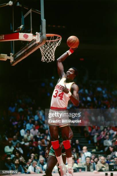 Hakeem Olajuwon of the Houston Rockets goes for a dunk against the Boston Celtics during an NBA game at the Compaq Center circa 1984 in Houston,...