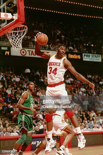 Hakeem Olajuwon of the Houston Rockets grabs a rebound against the Boston Celtics during an NBA game at the Compaq Center circa 1994 in Houston,...
