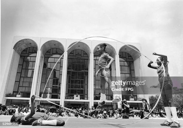 Three young girls jump rope double dutch style on stage in front of an audience outside the Metropolitan Opera House in the Lincoln Center Fountain...