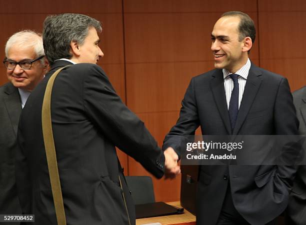 Greek Finance Minister Euclid Tsakalotos shakes hands with Cypriot Finance Minister Harris Georgiades during the Eurogroup meeting on Greece's...