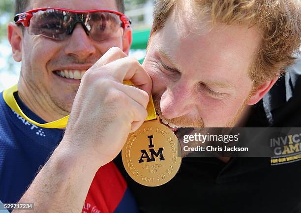 Prince Harry bites Jaco van Gass's gold medal at the road cycling event during the Invictus Games Orlando 2016 at ESPN Wide World of Sports on May 9,...