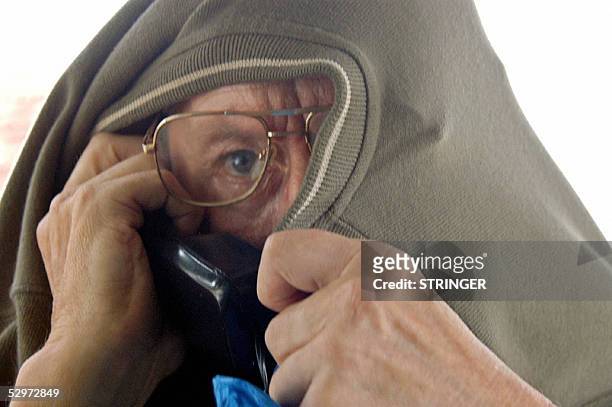 German national, Leo Brock attempts to hide his face, 24 May 2005 as he appears before the Kilifi resident Magistrate in Mombasa, to face a count of...