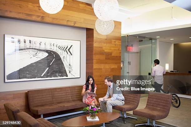 man and woman talking in office lobby - lobby foto e immagini stock