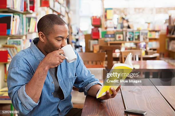 man drinking coffee and reading book - man holding book stock pictures, royalty-free photos & images
