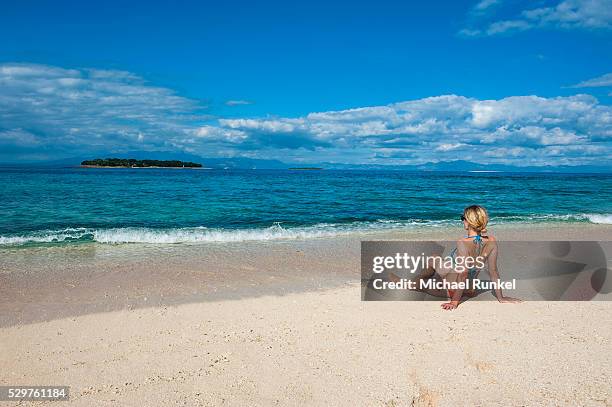 woman sitting on a the white sand beach of beachcomber island, mamanucas islands, fiji, south pacific, pacific - beachcomber island stock pictures, royalty-free photos & images