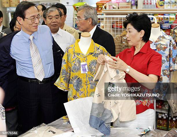 Japanese Chief Cabinet Secretary Hiroyuki Hosoda tries to put a short sleeve dress shirt, while Environment Minister Yuriko Koike helps him, for the...